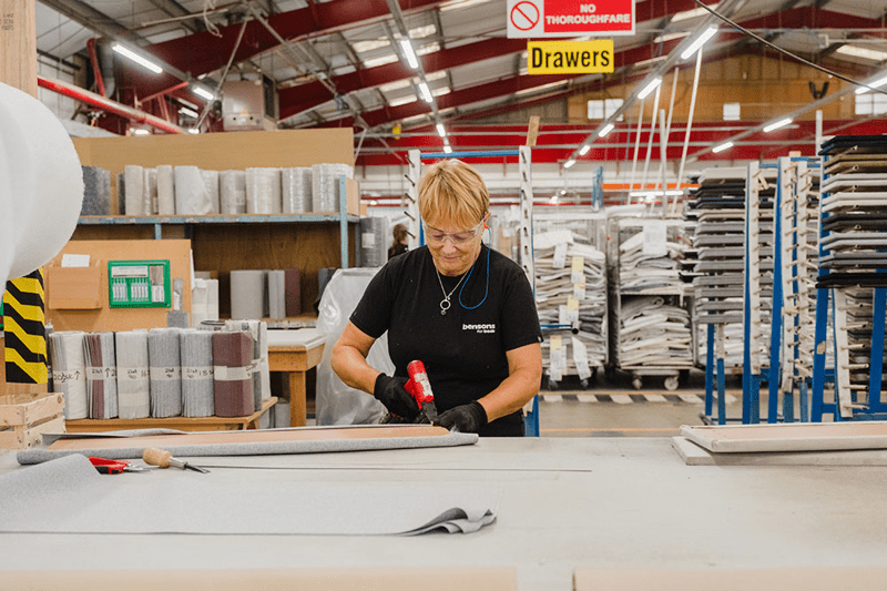 Woman working in a warehouse, using a tool