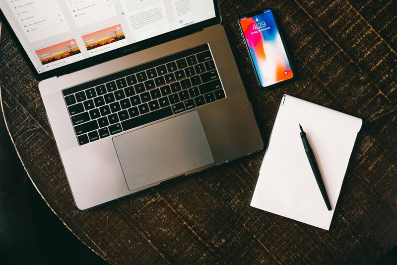 MacBook beside iPhone X on brown table