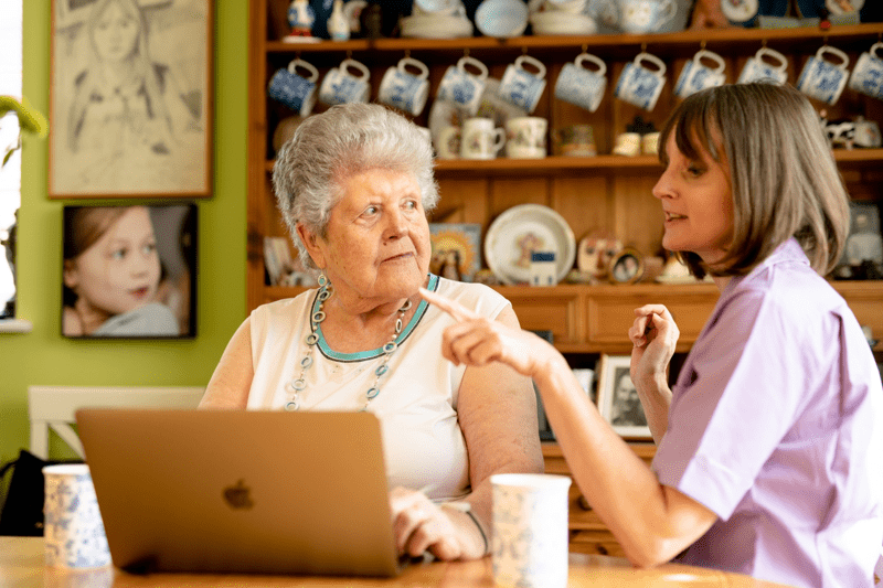 Care Professional with live in care client using a laptop