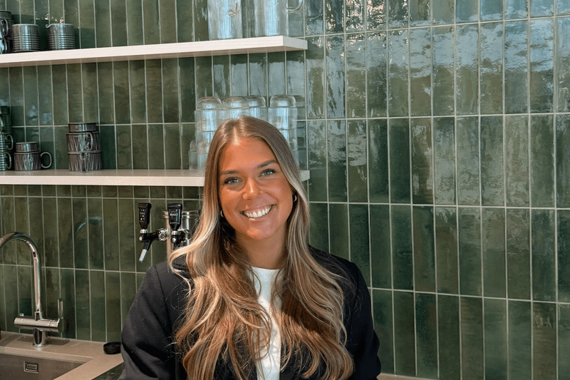 tjej ler i köket med en kaffekopp