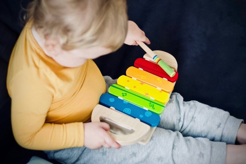 toddler playing wooden xylophone toy