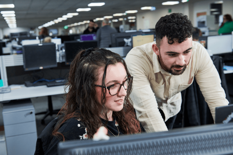 Male and female colleague in an office looking at a screen
