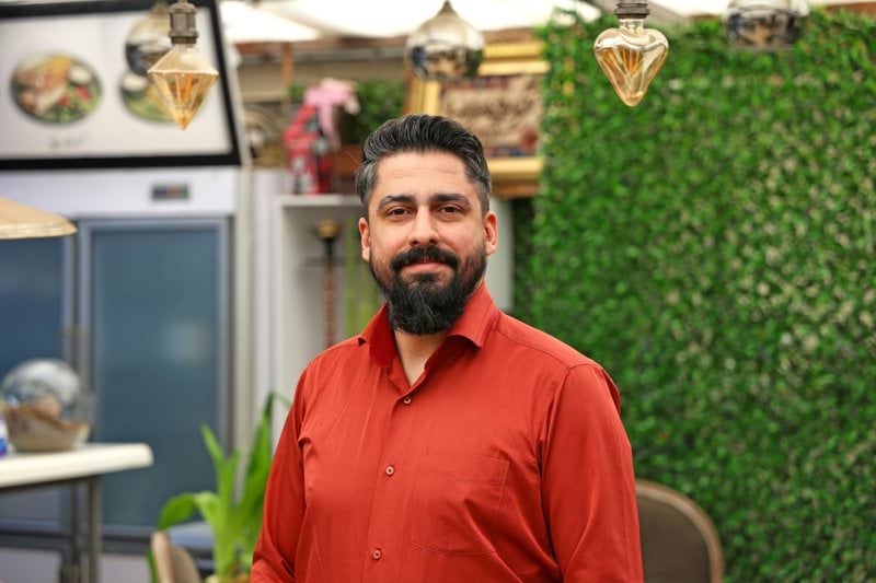 Man with beard in a red shirt smiling indoors