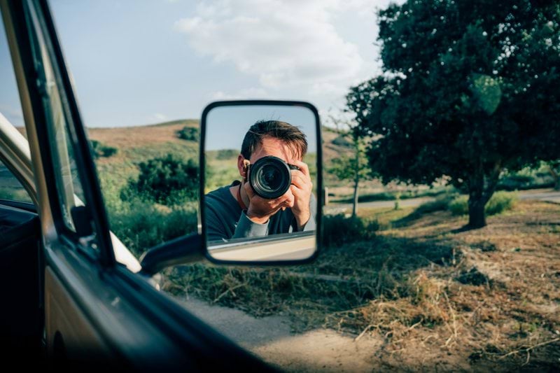 a man taking a picture of himself in a rear view mirror