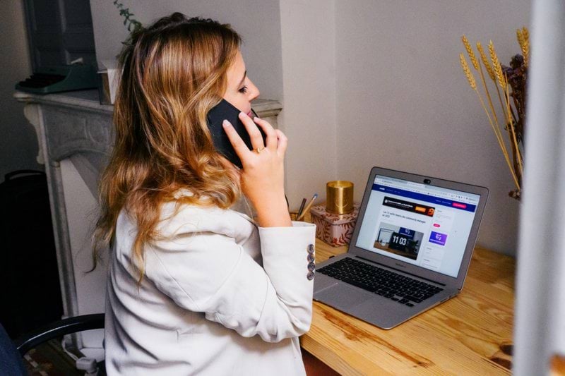 a woman sitting at a desk with a laptop and a phone