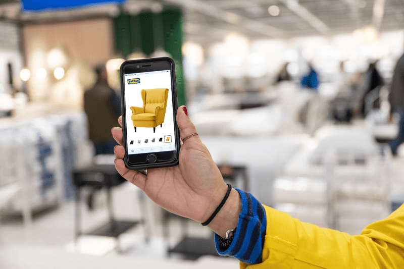 IKEA töötaja käsi hoiab nutitelefoni, mille ekraanil on IKEA veebipoe sait.