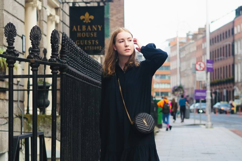 a woman leaning against a fence on a city street