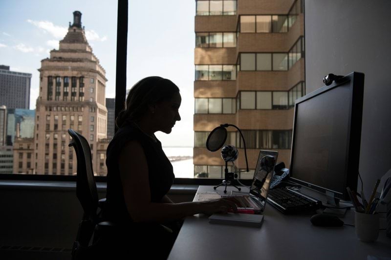 woman sitting in front of desk with computer monitor and keyboard on top