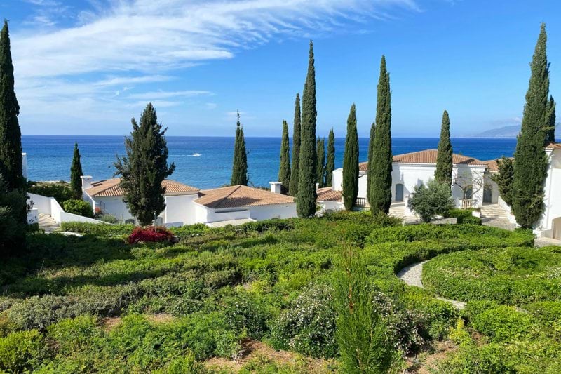 white and brown house near green trees under blue sky during daytime