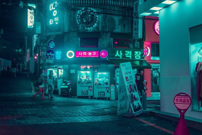 group of people walking on the street near buildings at night time