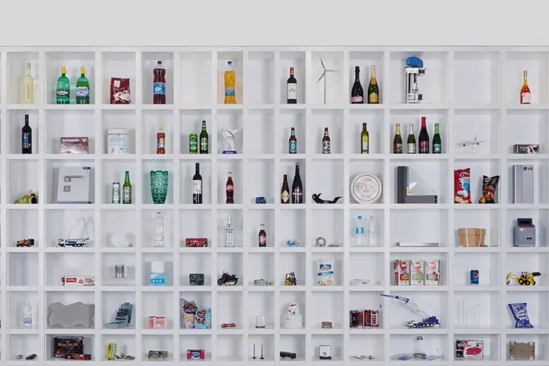 Wall with multiple small square shelves holding various bottles, boxes, and small objects arranged in a grid