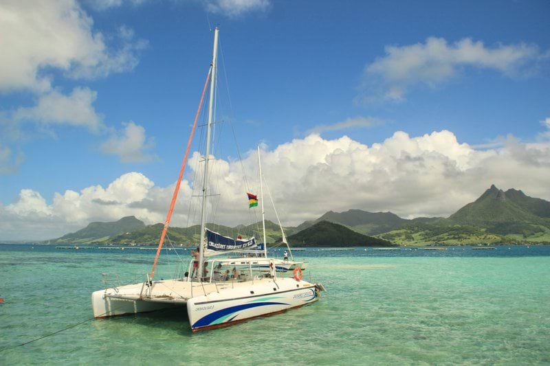 a sailboat in the water with mountains in the background