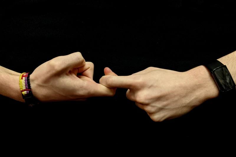 two hands holding each other with bracelets on them