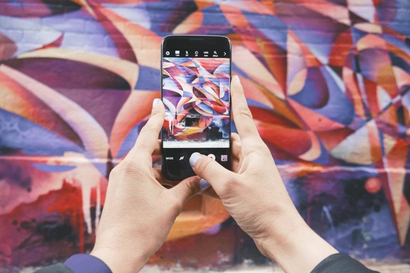 person holding Android smartphone and taking a photo of abstract wall during daytime