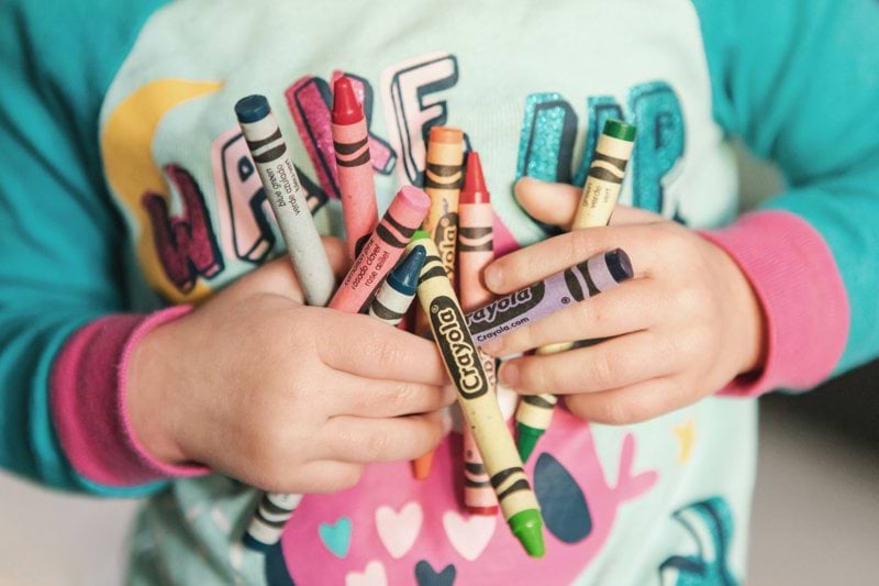 toddler holding assorted-color Crayola lot