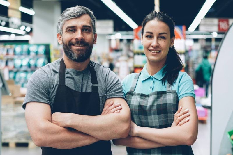 Two grocery store employees smiling at the camera.