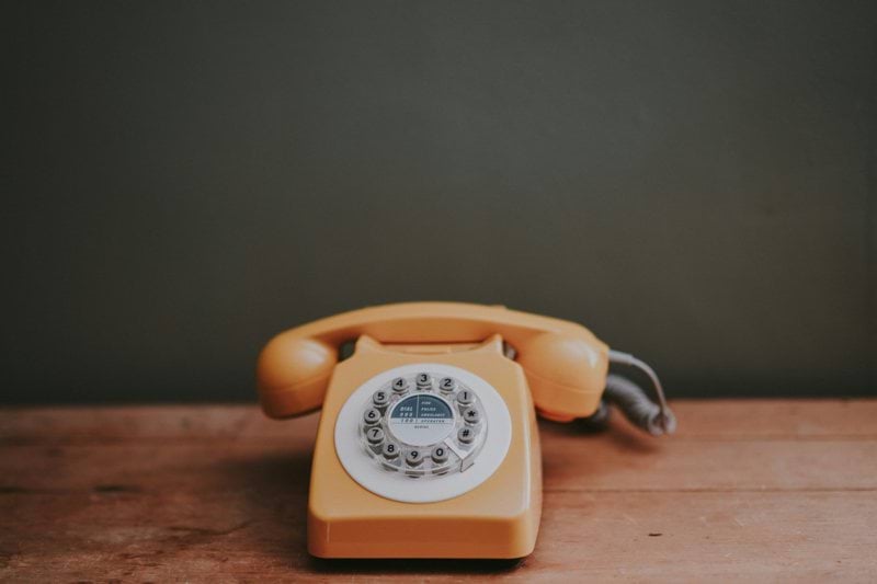 brown rotary dial telephone in gray painted room