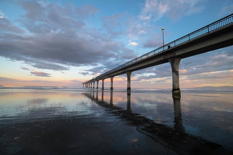 gray concrete bridge over body of water under cloudy sky during daytime