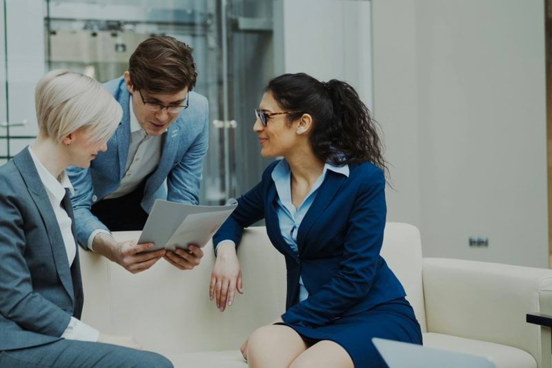 Three business people in suits discussing documents.