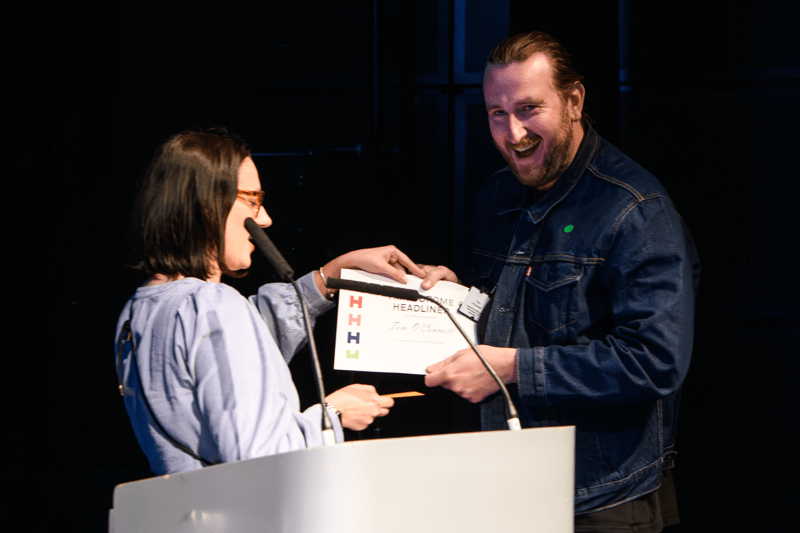 Person handing award celebrating staff achievements to another member of staff.