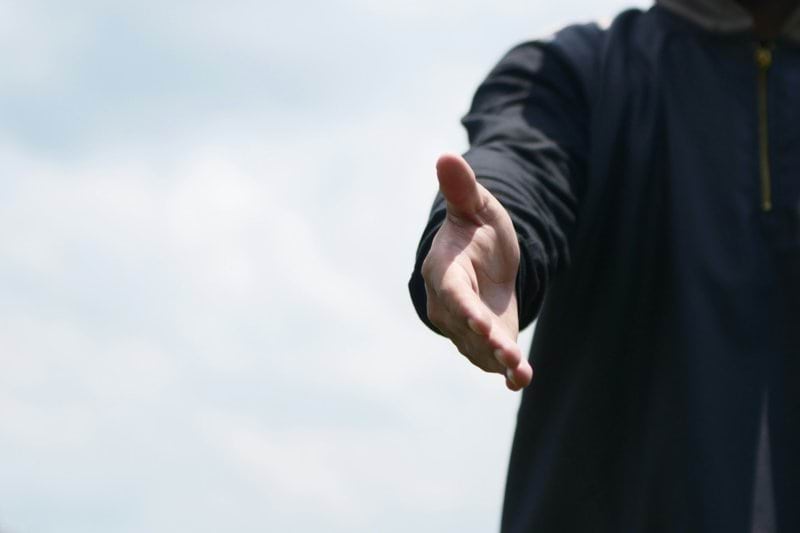 a man in a hoodie holding out his hand
