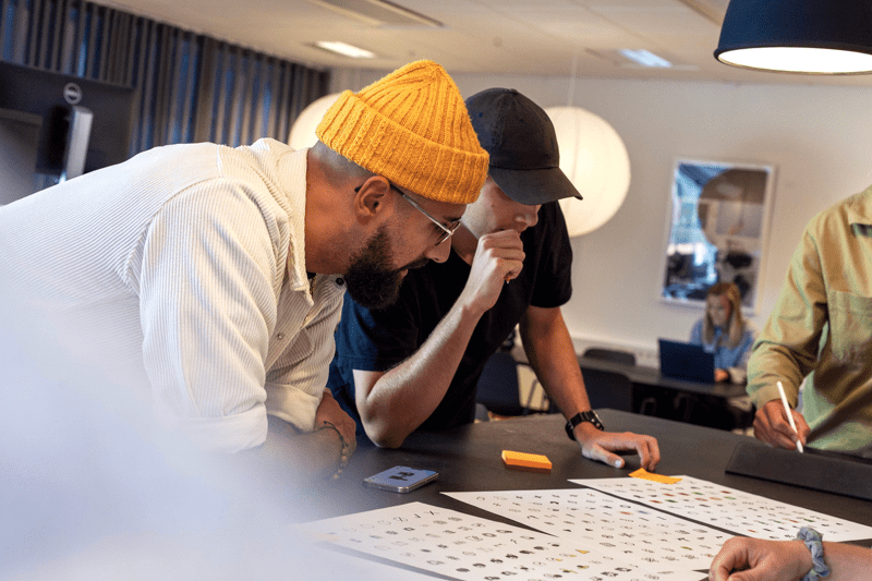 Group of colleagues gathered around a table, reviewing design materials together