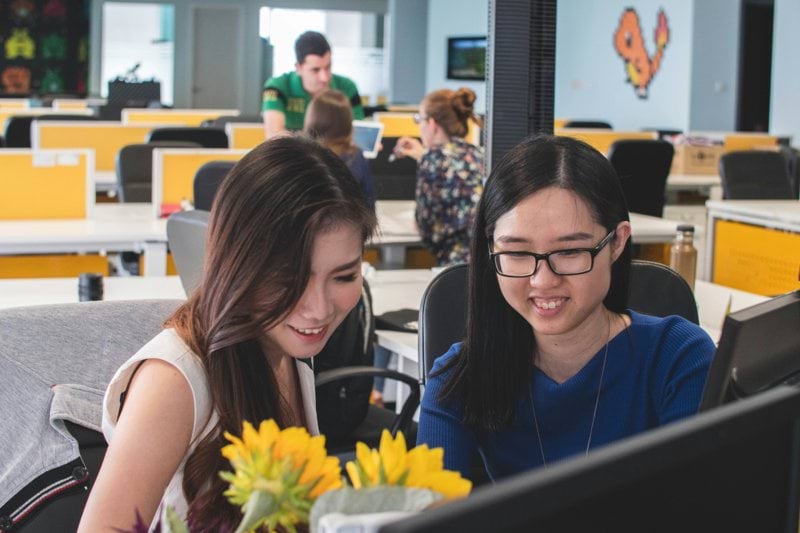 selective focus photography of two women in front of computer monitor