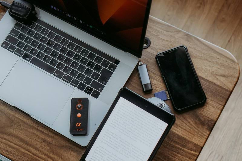 Laptop, tablet, and phone on a wooden desk.