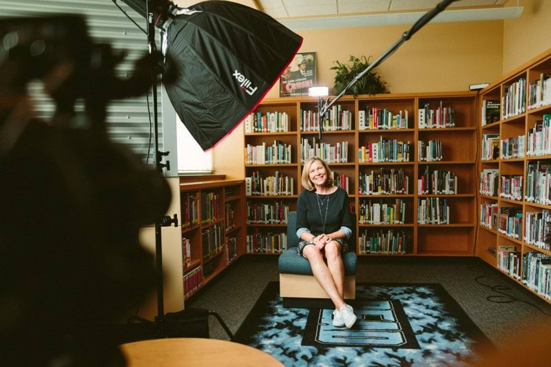woman sitting on armless chair with light between bookcases in room