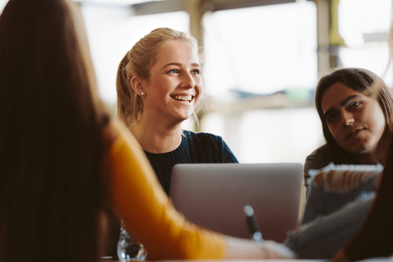Three women in front of a computer, smiling