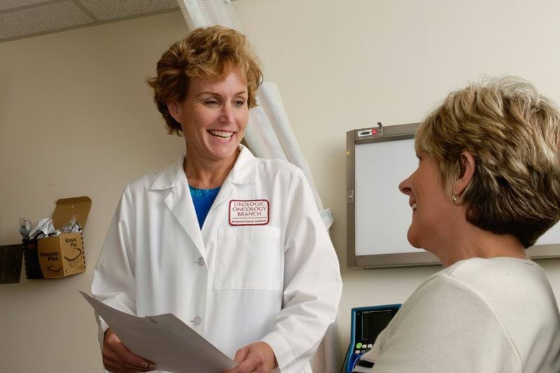 woman in white scrub suit holding gray laptop computer