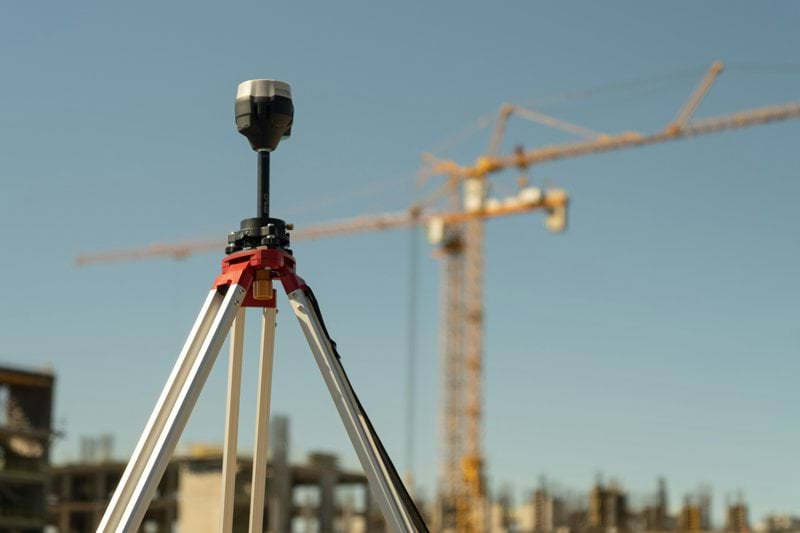 a tripod with a camera attached to it in front of a construction site