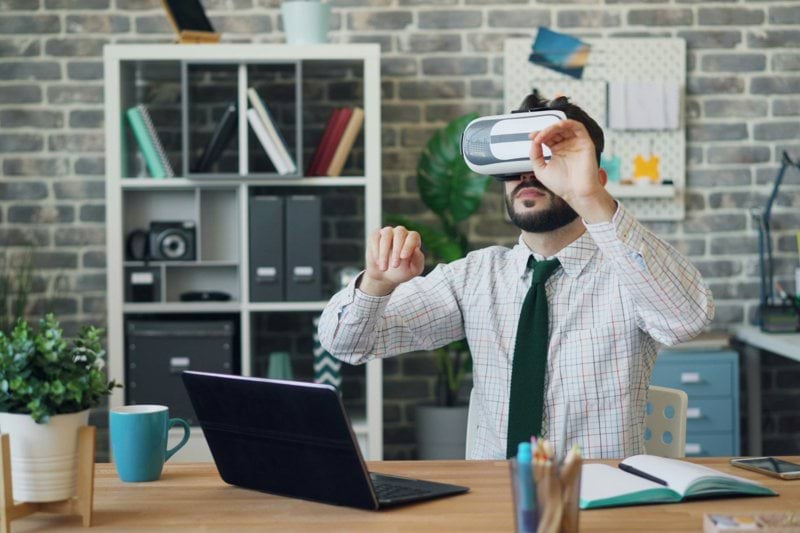 a man in a tie is using a laptop while wearing a virtual headset