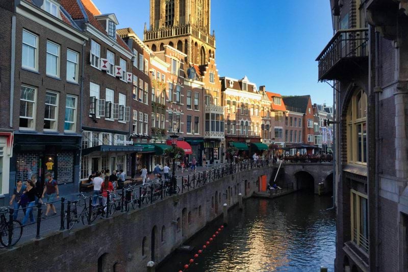 people walking on sidewalk beside river during daytime