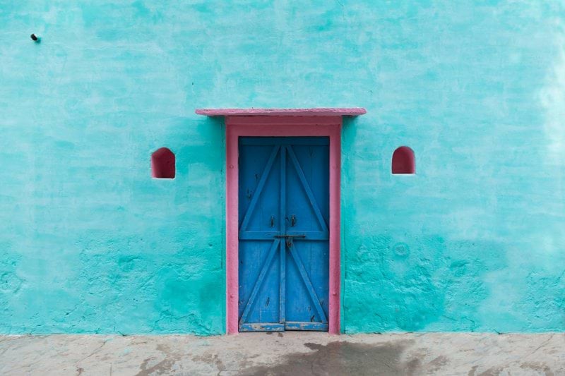 red wooden door on blue concrete wall