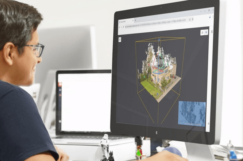 Frau sitzt vor dem Desktop PC und schaut sich eine Punktwolke von einem Gebäude an