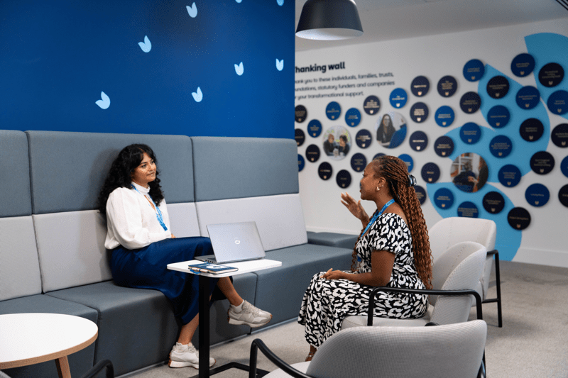Two colleagues having a conversation in an office seating area.
