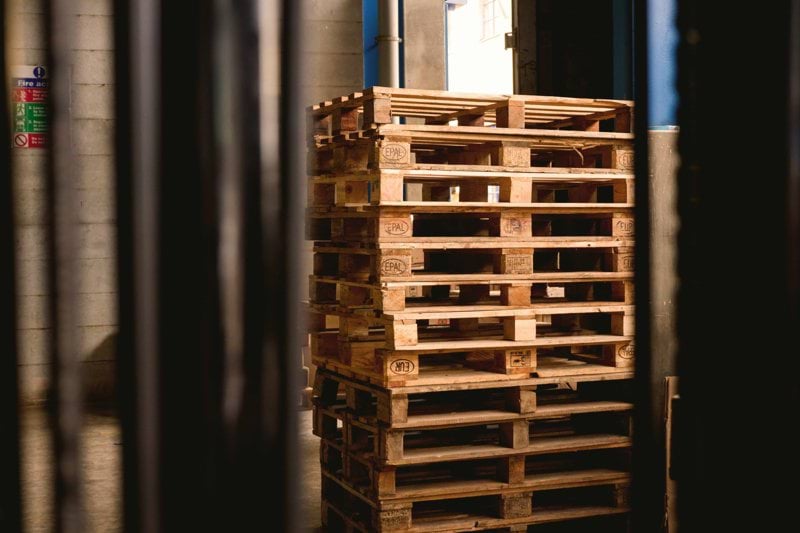 selective focus photography of piled brown wooden pallets