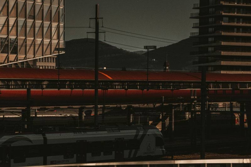 a red train traveling down train tracks next to tall buildings