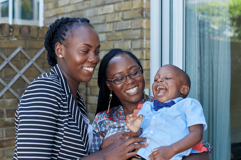 Two women and a young boy embracing and laughing