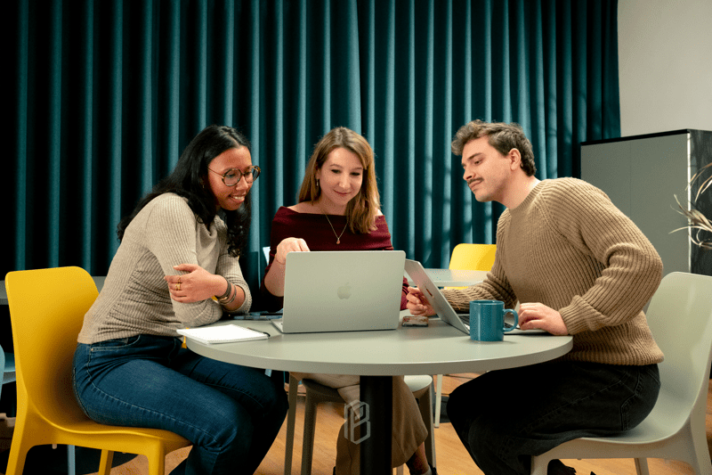 a team of people chatting in front of a computer