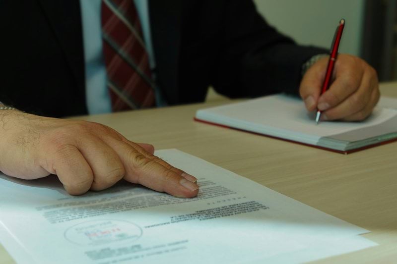 a man in a suit signing a document with a pen