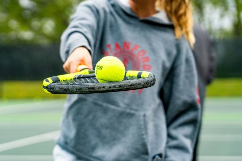 a person holding a tennis racket and two tennis balls
