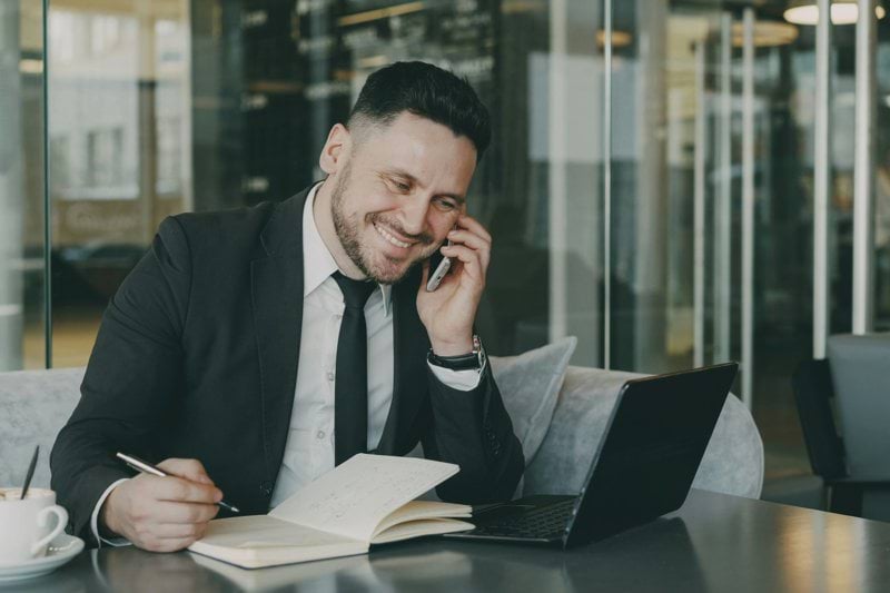 Man in suit talking on phone while writing