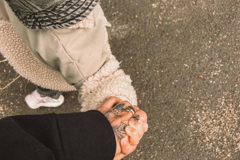 A person standing on a sidewalk holding their hands together