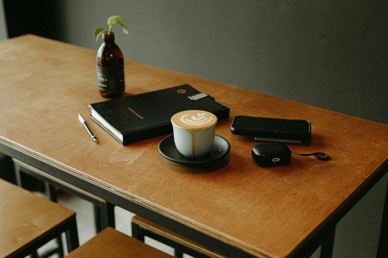 Coffee, notebook, and accessories on table.