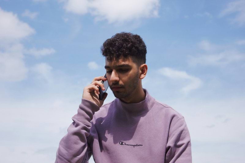 a man in a purple shirt talking on a cell phone