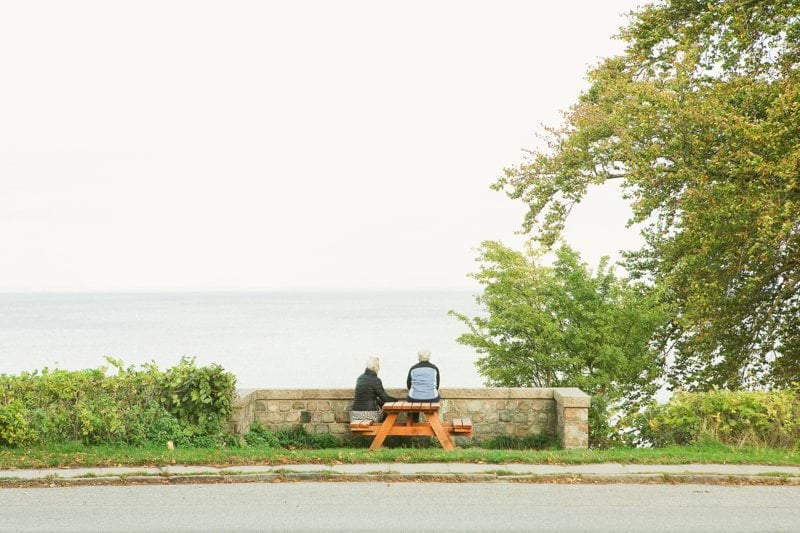 a couple of people sitting on a bench by the water