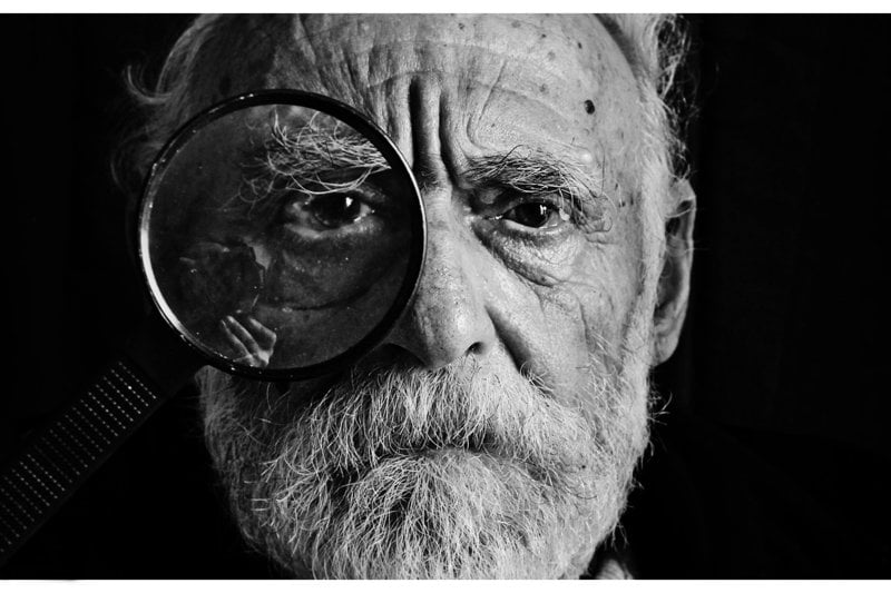 grayscale photo of man using magnifying glass