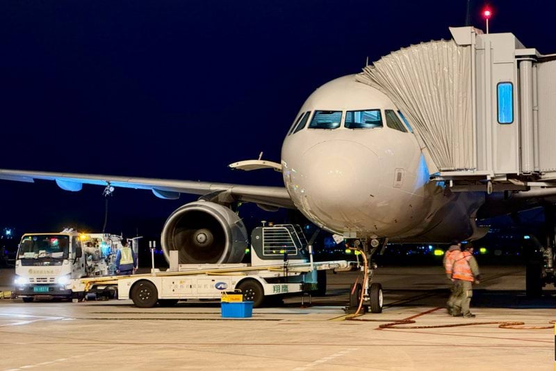 Airplane connected to a jet bridge at night